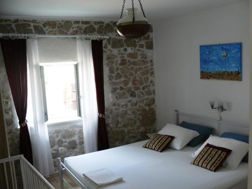 a bedroom with a white bed and a window at Mimi in Jadranovo