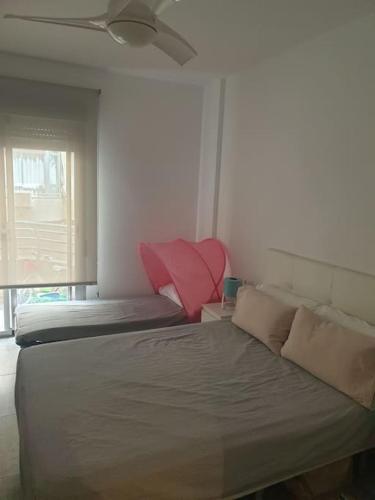 1 dormitorio con 2 camas y almohada roja en piso playa, en Santa Pola