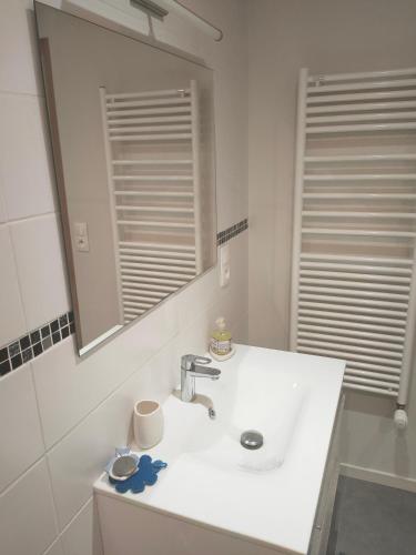 une salle de bain blanche avec un lavabo et un miroir dans l'établissement Beau studio dans la vallée de CHAMONIX, aux Houches