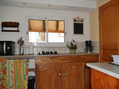 une cuisine avec des armoires en bois et une fenêtre dans l'établissement les Jéhans, à Châteauroux-les-Alpes