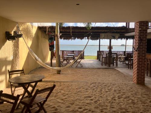 a patio with a hammock and tables and the ocean at SOS Kite Hostel in Itarema
