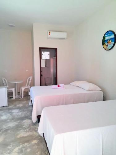 a room with two beds and a table and a mirror at Pousada Flor da Barra in Maragogi