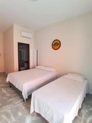 two beds in a room with white walls at Pousada Flor da Barra in Maragogi