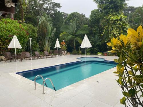 a swimming pool with tables and chairs and umbrellas at Casa Praia Guaratuba - Bertioga in Bertioga