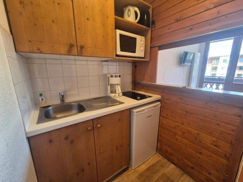 une petite cuisine avec un évier et un micro-ondes dans l'établissement Studio cosy à Tignes Val Claret - 10m des pistes avec balcon, idéal pour 4 personnes - FR-1-502-429, à Tignes