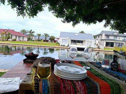 a table with plates and wine glasses next to a pond at Jeffreys Bay - Life on the Canals in Jeffreys Bay