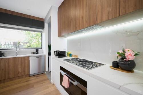 a white kitchen with a stove and a sink at Preston Lux House 5 bed 5 bath in Melbourne