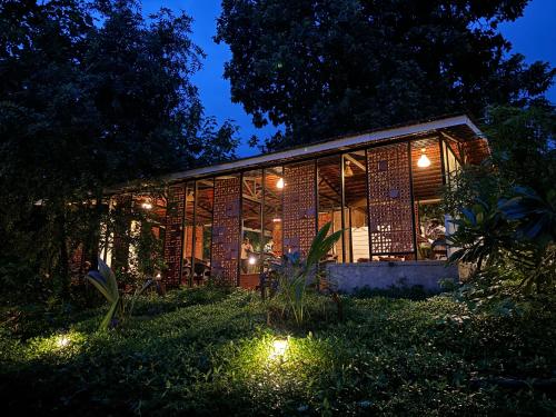 a brick house with lights in the yard at night at Hidden Haven - The Goan Getaway in Dhamni