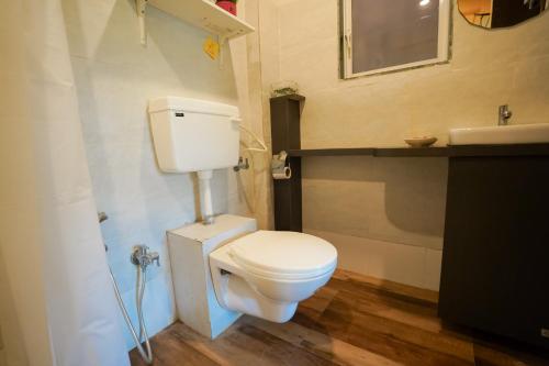 a bathroom with a white toilet and a sink at Hidden Haven - The Goan Getaway in Dhamni