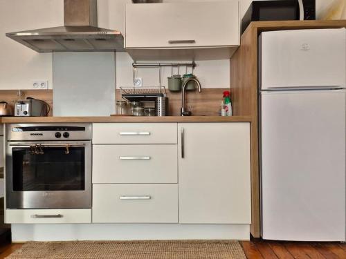 une cuisine avec des armoires blanches et un réfrigérateur blanc dans l'établissement l'Angevin - hypercentre - WiFi, à Sorges