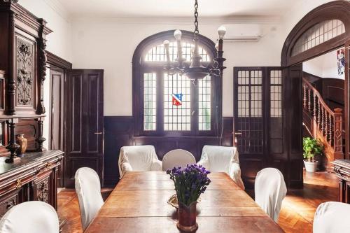 a dining room with a wooden table and white chairs at Maison Depla with rooftop, Jacuzzi, pool, and BBQ in Buenos Aires