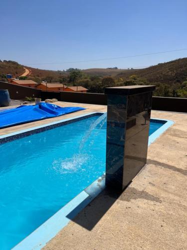 Una piscina con un pilar de piedra al lado. en Chácara do Pepê, en São Roque de Minas