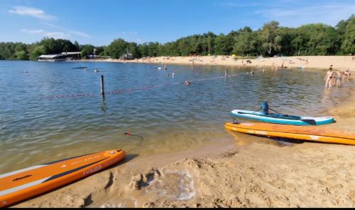 a beach with two kayaks and people in the water at Elseblick in Schüttorf