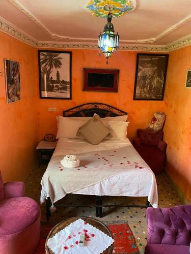 a bedroom with a bed and two chairs and a chandelier at Riad Jennah Rouge in Marrakech