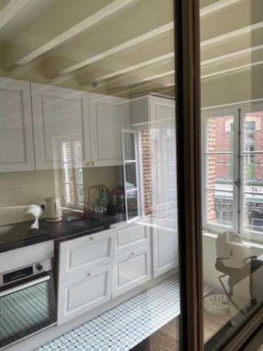 d'une cuisine avec des placards blancs et une porte en verre. dans l'établissement Le fournil, à Veules-les-Roses