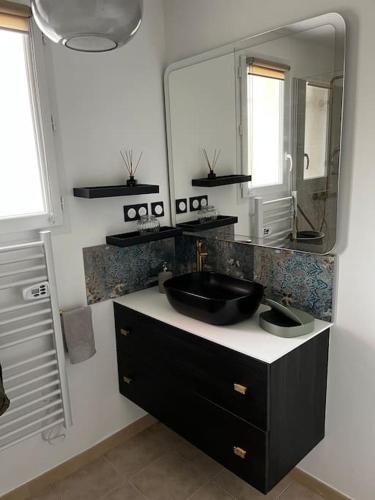 une salle de bain avec un lavabo noir et un miroir dans l'établissement Villa Simone proche Uzes, à Blauzac