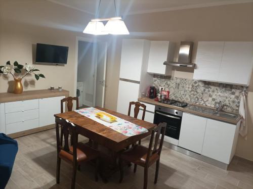 a kitchen with a wooden table and a kitchen with white cabinets at Casa Nenè in Trabia