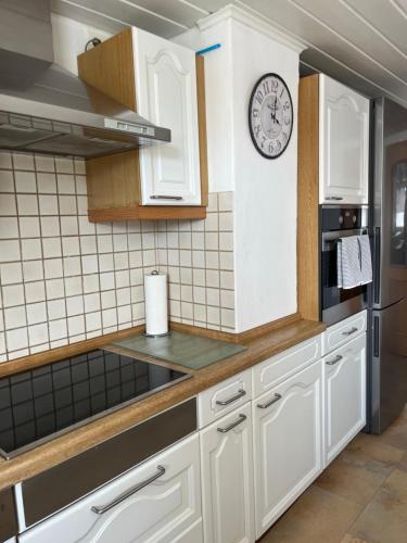 a kitchen with white cabinets and a clock on the wall at Allgäu Apartment in Memmingen
