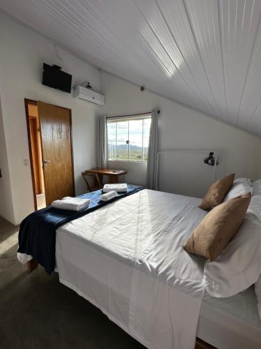 a large white bed in a room with a window at Pousada/Camping Mirante Serrano in Alto Paraíso de Goiás