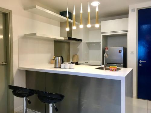 a kitchen with a counter and two stools in it at Sunset Seaview Vacation Condos Infinity Avenue in Kota Kinabalu