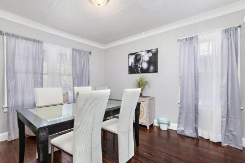 a dining room with a glass table and white chairs at Jazzy Charmer with 3 Queen BedsJazzy Charmer in Kansas City