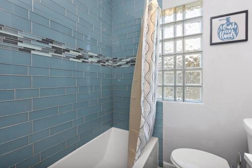 a blue tiled bathroom with a toilet and a tub at Jazzy Charmer with 3 Queen BedsJazzy Charmer in Kansas City
