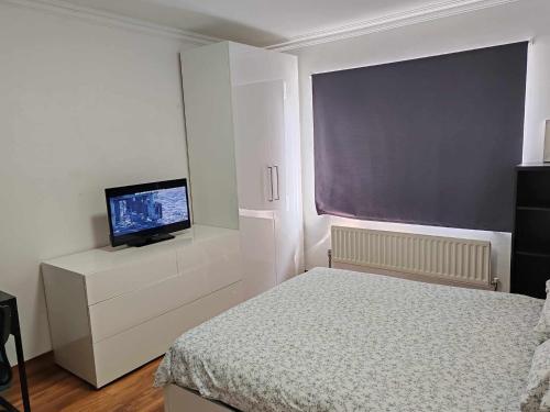 a bedroom with a bed and a flat screen tv at Two bedroom apartment in Dollis Hill in London