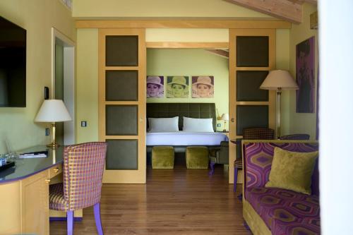a bedroom with a bed and a desk and a chair at Parc Hotel Flora S in Riva del Garda