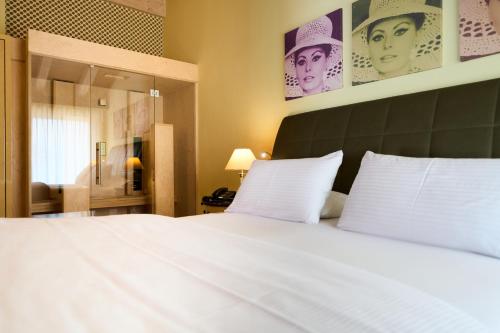 a bedroom with a large white bed and a mirror at Parc Hotel Flora S in Riva del Garda