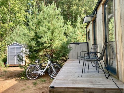 a bike parked on a porch with a tree at Przystanek Naglady Warmia- całoroczny, duża leśna działka in Naglady