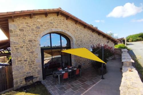une terrasse avec un parasol jaune devant un bâtiment dans l'établissement Gîte Le Bouton d'Or 3 étoiles 8 kms PuyDuFou, à Chambretaud