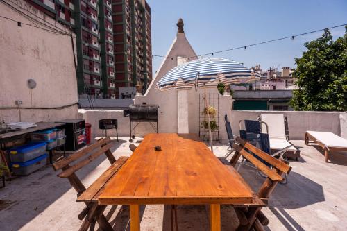 a wooden table on a patio with an umbrella at Maison Depla with rooftop, Jacuzzi, pool, and BBQ in Buenos Aires