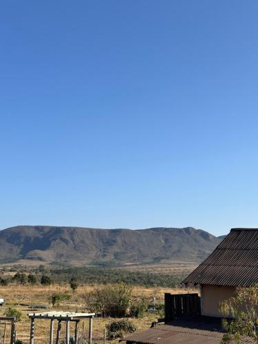 a picnic table and a building with mountains in the background at Pousada/Camping Mirante Serrano in Alto Paraíso de Goiás