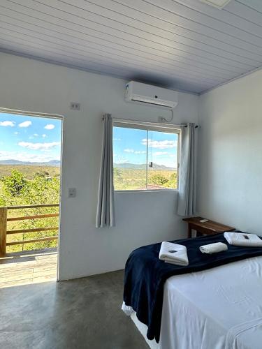 a bedroom with a bed and a large window at Pousada/Camping Mirante Serrano in Alto Paraíso de Goiás