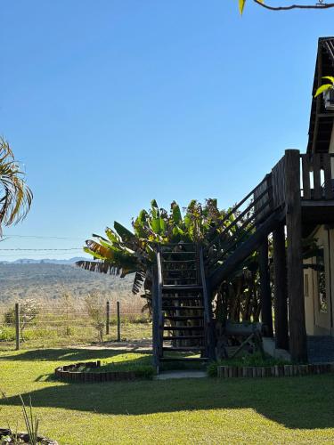 a wooden staircase leading to a house with a tree at Pousada/Camping Mirante Serrano in Alto Paraíso de Goiás