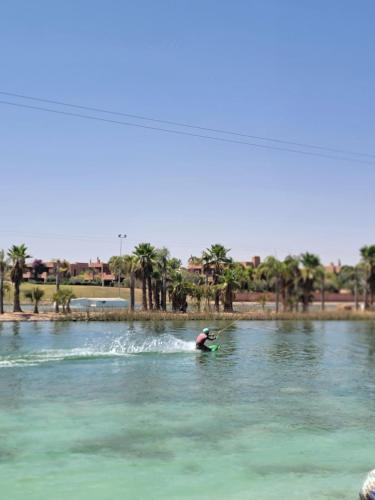 a person riding a wave on a surfboard in the water at les jardins d'atlas waky palm golf in Marrakech