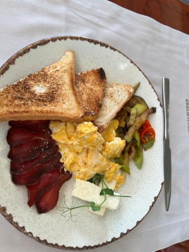 a plate of breakfast food with toast and vegetables at Agropensiunea Vila Cristina in Niculiţel
