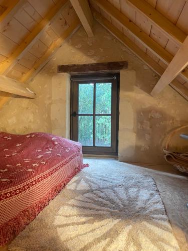Cette chambre mansardée comprend un lit et une fenêtre. dans l'établissement Immersion dans une loge de vigne, à Ingrandes-de-Touraine