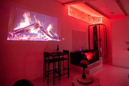 Cette chambre rouge dispose d'une télévision, d'une table et de chaises. dans l'établissement Maisonnette romantique avec balnéothérapie - Redroom, à Marseille