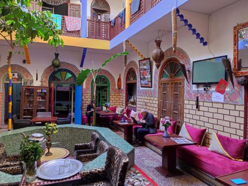 sala de estar con muebles de color púrpura y TV de pantalla plana. en Riad Dia, en Marrakech