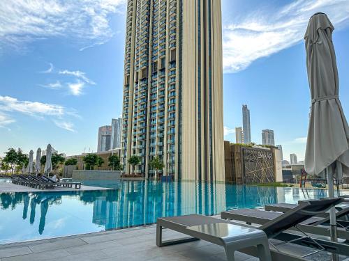 a swimming pool with lounge chairs and a large building at Amazing Burj Khalifa Views with Direct Dubai Mall Access, 2BR Apartment in Downtown Dubai in Dubai