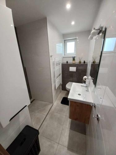 a white bathroom with a sink and a toilet at Chata Junáčik Oravice in Oravice
