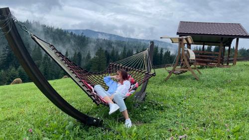 a woman sitting in a hammock in a field at Мелодія Гір .Апартаменти з видом на гори . in Vorokhta