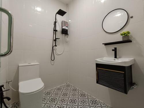 a bathroom with a toilet and a sink and a mirror at Alameen Boutique Hotel in Kangar