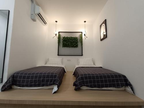 two beds in a room with a picture on the wall at Alameen Boutique Hotel in Kangar