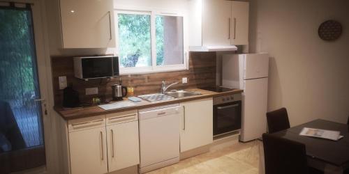 une cuisine avec des armoires blanches, un évier et un réfrigérateur dans l'établissement Gîte L'hirondelle à St Antonin du Var, 2 chambres, à Masseboeuf