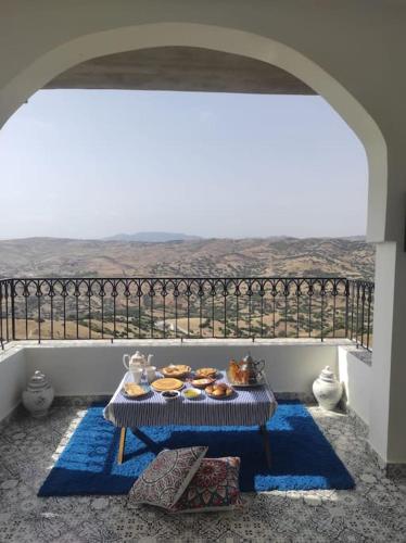 a table with a tray of pastries on a balcony at Dar Anjra in El Jandak