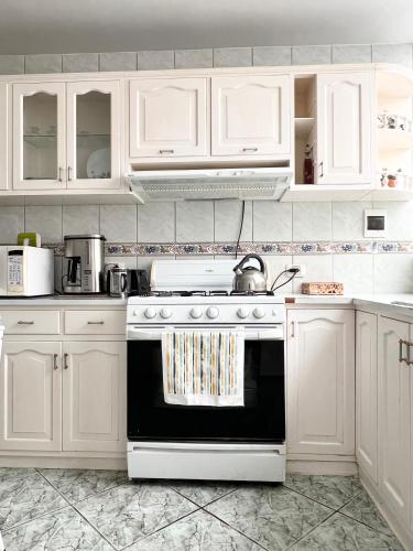 a kitchen with white cabinets and a stove at Hermosa casa a 15 min de Paracas in Pisco