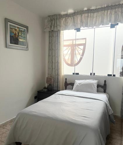 a bedroom with a large white bed with a window at Hermosa casa a 15 min de Paracas in Pisco