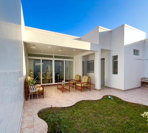 a large white house with a patio with chairs at Hermosa casa a 15 min de Paracas in Pisco